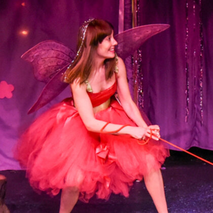 Twinkle in a coral petal dress with sparkling wings, leaning back hard on a red leash.